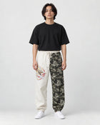 Model wearing the cream and wave-print jogger pants with a black tee and white sneakers, front view