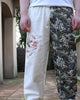 Man wearing the cream and wave-print jogger pants, with the embroidered dragon on the thigh and gathered cuffs