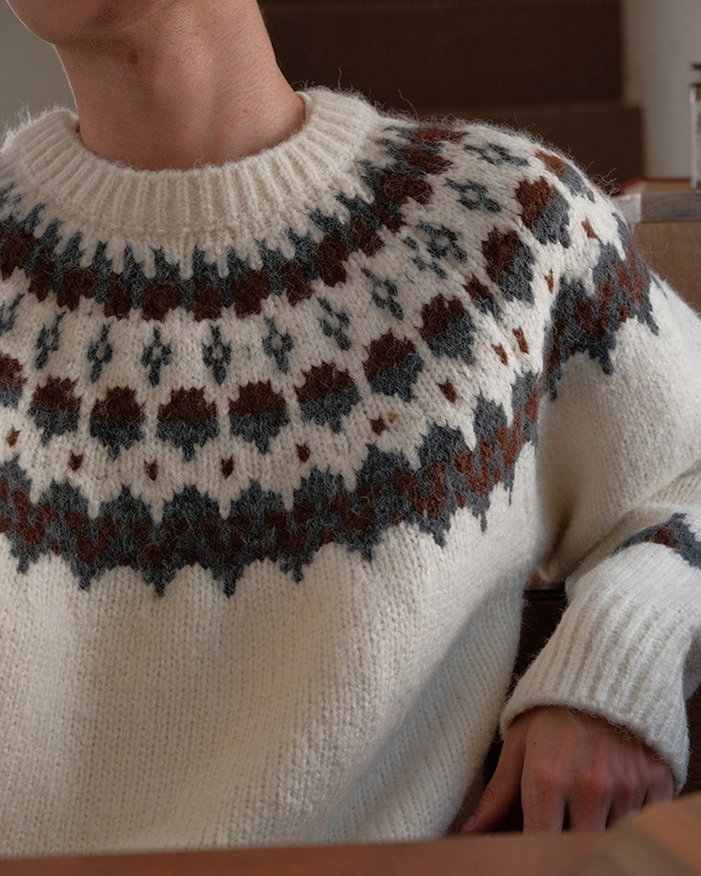 Close view of the round yoke in brown, charcoal and blue-gray on the cream sweater