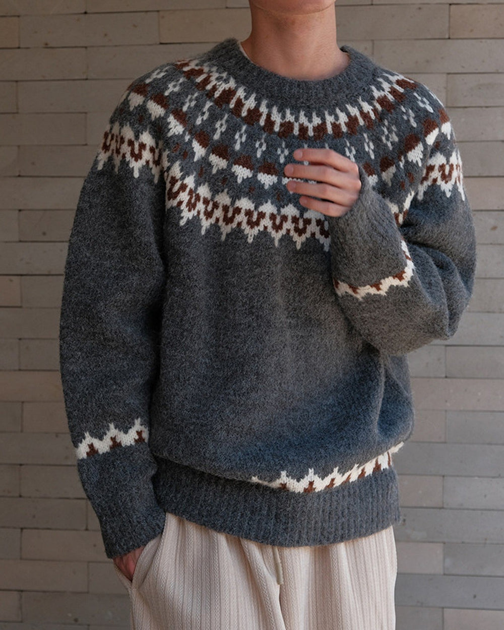 Charcoal gray fair-isle sweater with the zigzag cuff band, hand at the chest