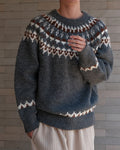 Charcoal gray fair-isle sweater with the zigzag cuff band, hand at the chest