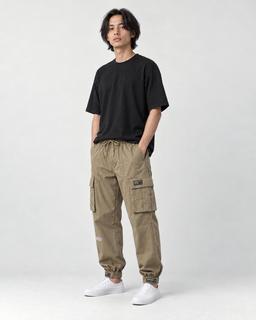 Model wearing the khaki cargo joggers with a black tee and white sneakers, three-quarter view