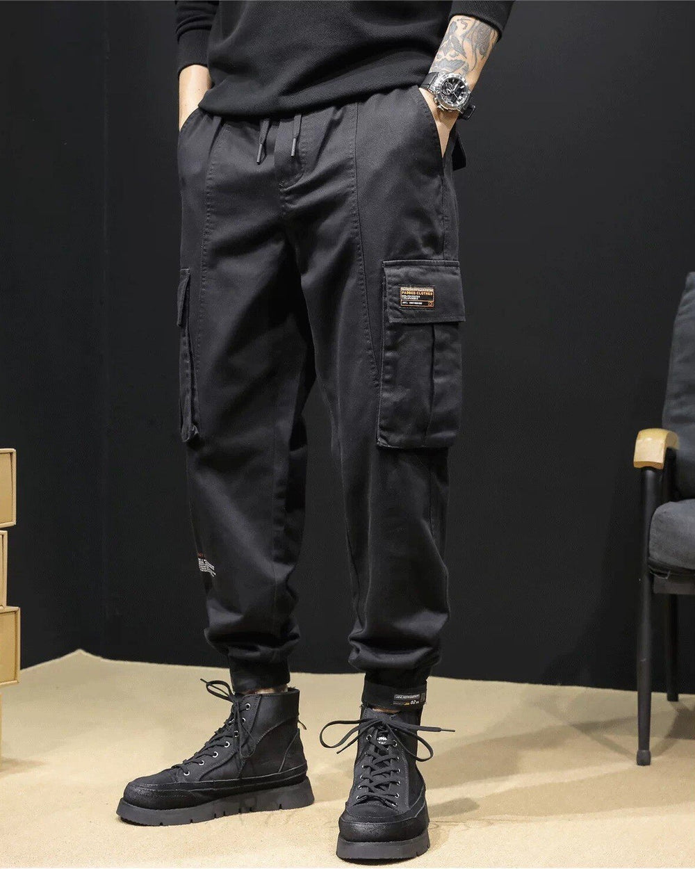 Black cargo joggers with a flap pocket and woven label, worn with black boots