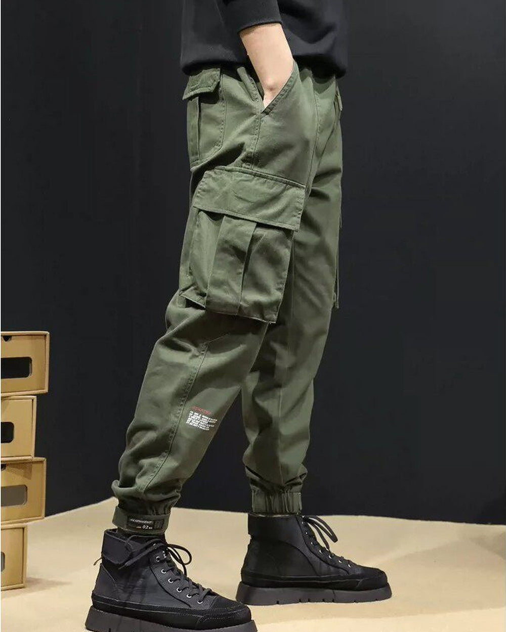 Side view of the army green cargo joggers with the flap pocket and the printed text on the lower leg