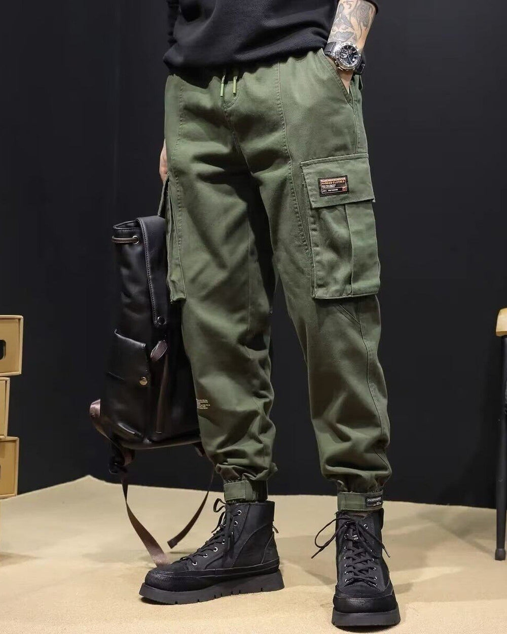 Army green cargo joggers with a flap pocket and woven label, worn with black boots