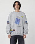 Model wearing the light gray label-print crewneck sweatshirt with dark jeans, front view