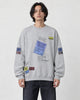 Model wearing the light gray label-print crewneck sweatshirt with dark jeans, front view