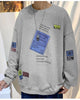 Light gray crewneck sweatshirt with a tilted blue label, a yellow tag and barcode patches on the sleeves