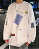 White crewneck sweatshirt with a tilted blue label, a yellow tag and a barcode patch on the sleeve, close view