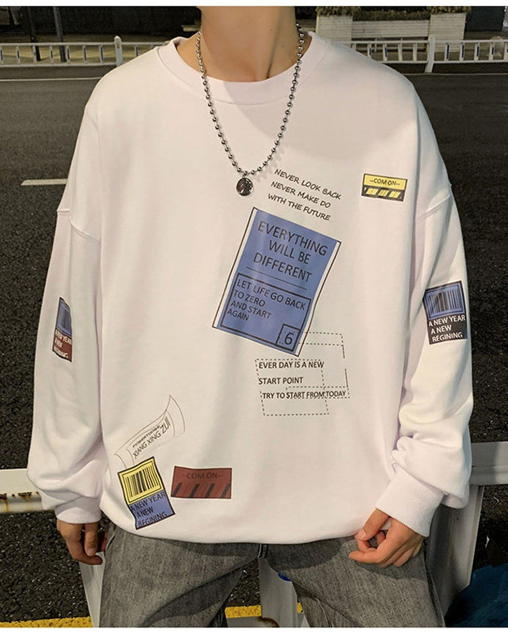 White crewneck sweatshirt, front view, with the blue label, a dotted text box and two small tags at the hem