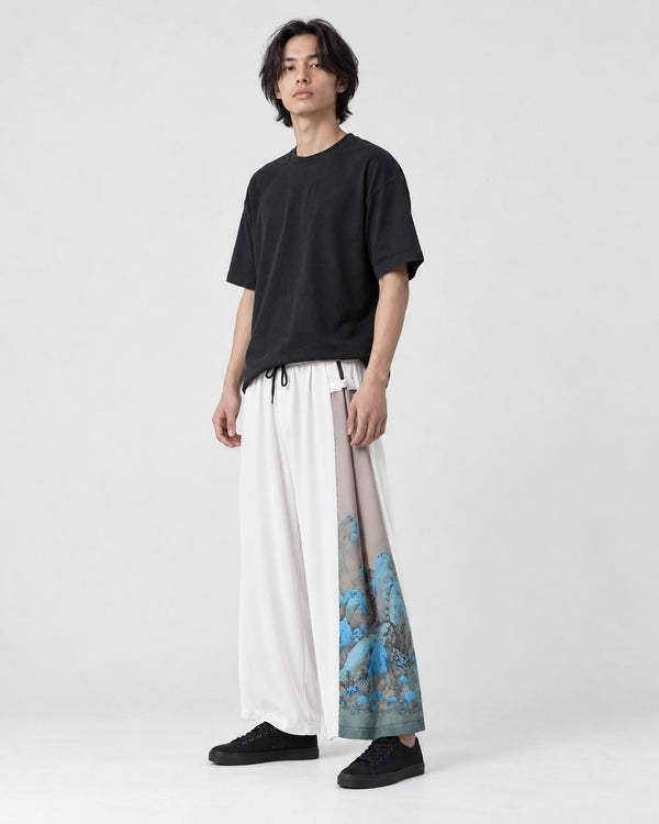 Model wearing the ivory white hanfu-inspired wide-leg pants with a black tee and black sneakers, three-quarter view