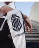 Close view of the hexagon emblem and script lettering on the white lower leg of the black joggers