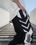 Black joggers with white arrow-shaped chevron panels down the thigh and a white lower leg with an emblem
