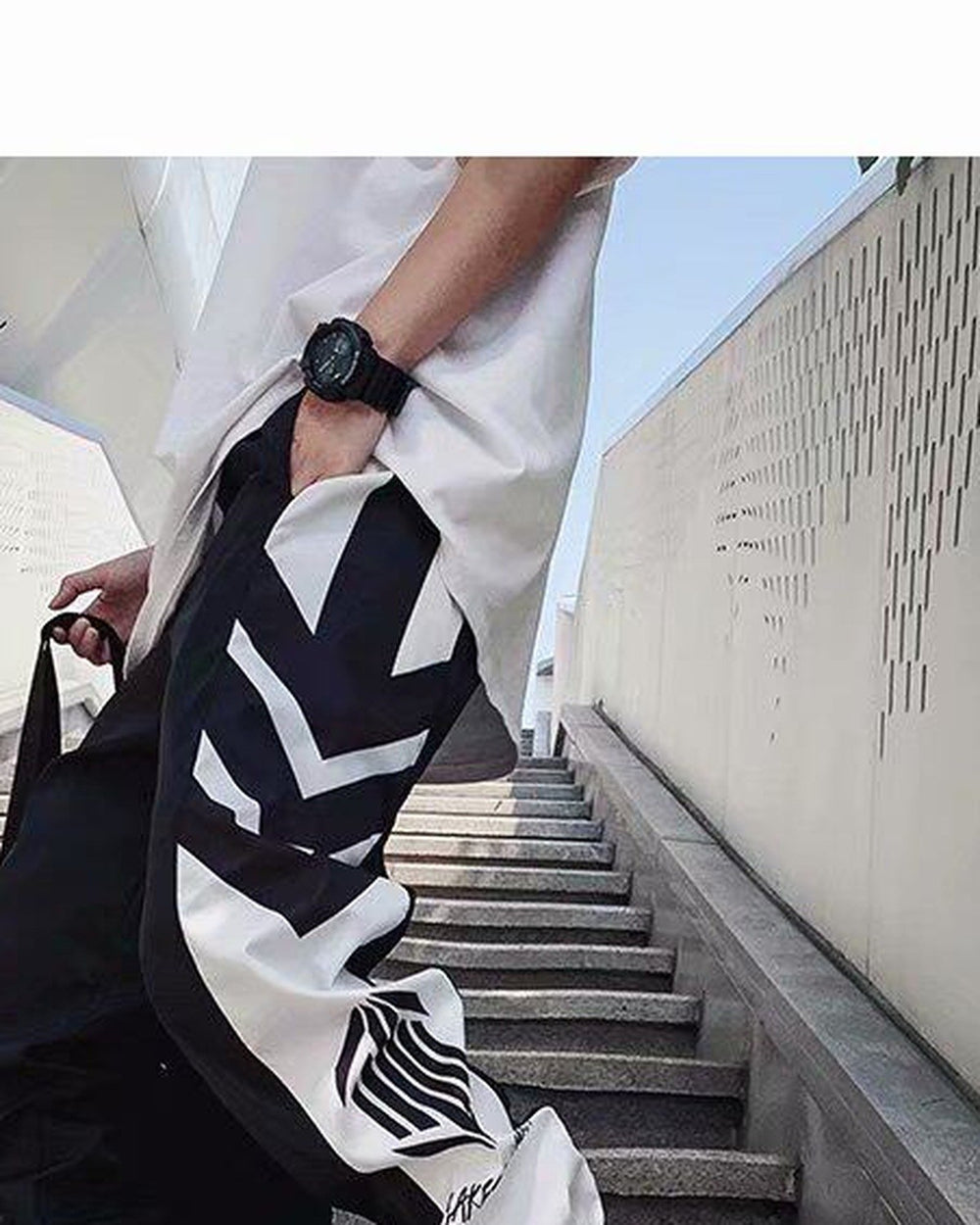 Side view of the black joggers showing the white chevron panel and the striped hexagon emblem