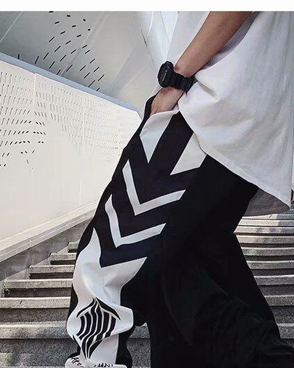 Black joggers with white chevron panels, worn in a step, showing the thigh and the lower leg panel