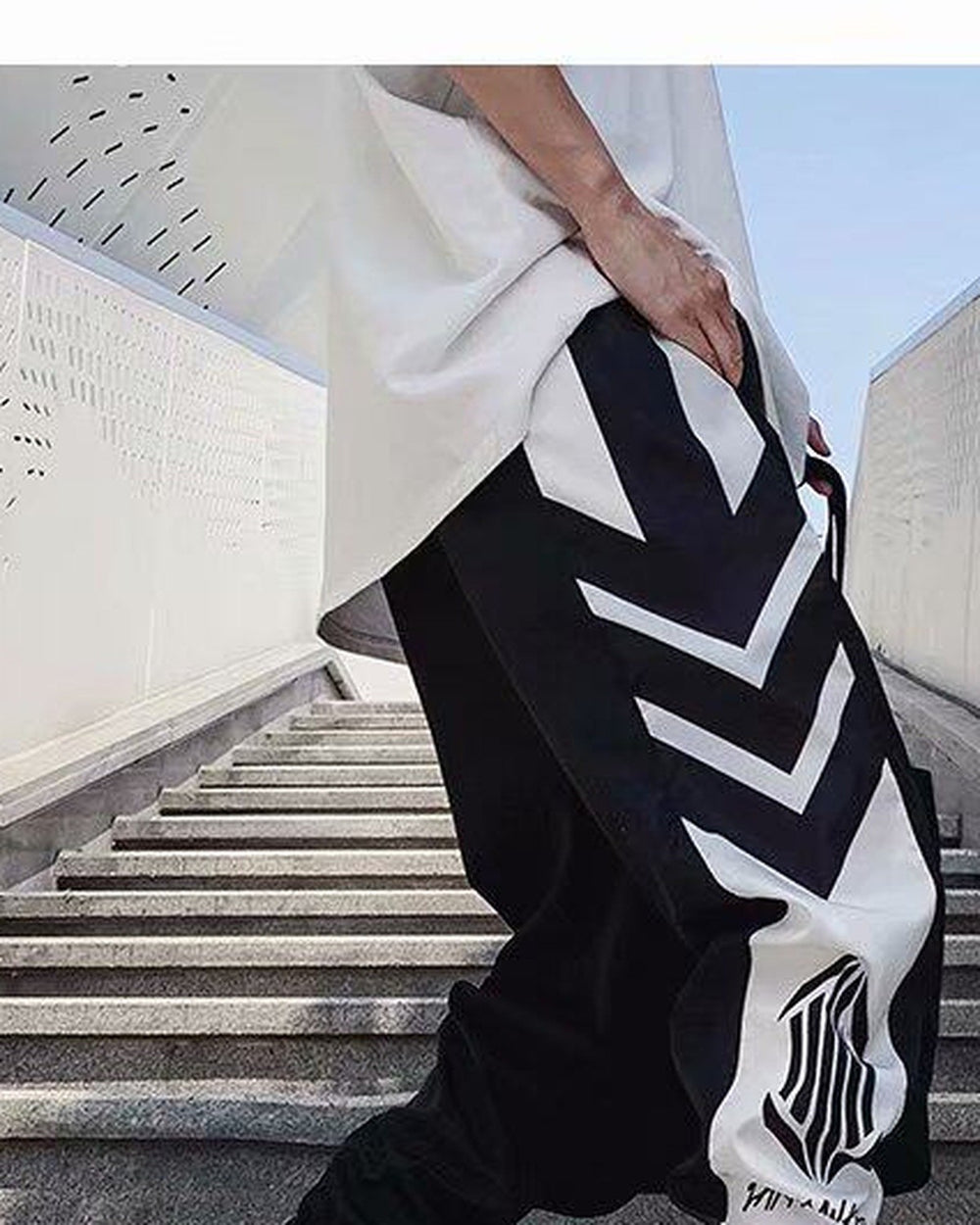 Black joggers with white chevron stripes and a white lower-leg panel with an emblem, front view