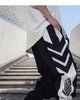 Black joggers with white chevron stripes and a white lower-leg panel with an emblem, front view
