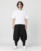 Model wearing the black layered drop-crotch harem pants with a white tee and white sneakers, front view