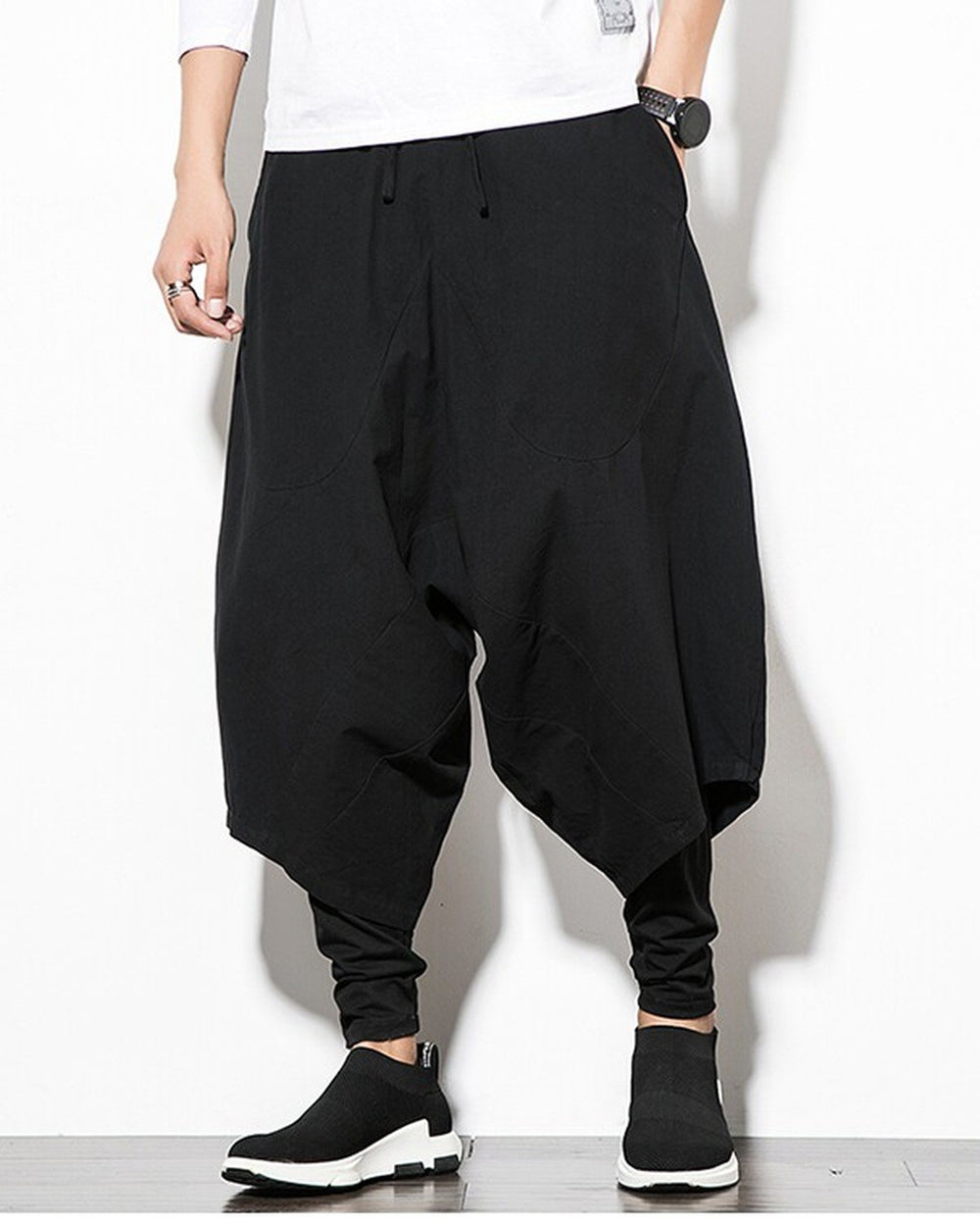 Black layered drop-crotch harem pants with a fitted black inner layer, worn with a white tee and black sock sneakers