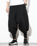 Black layered drop-crotch harem pants with a fitted black inner layer, worn with a white tee and black sock sneakers