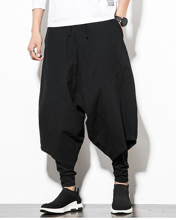Black layered drop-crotch harem pants with a fitted black inner layer, worn with a white tee and black sock sneakers