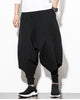 Black layered drop-crotch harem pants with a fitted black inner layer, worn with a white tee and black sock sneakers