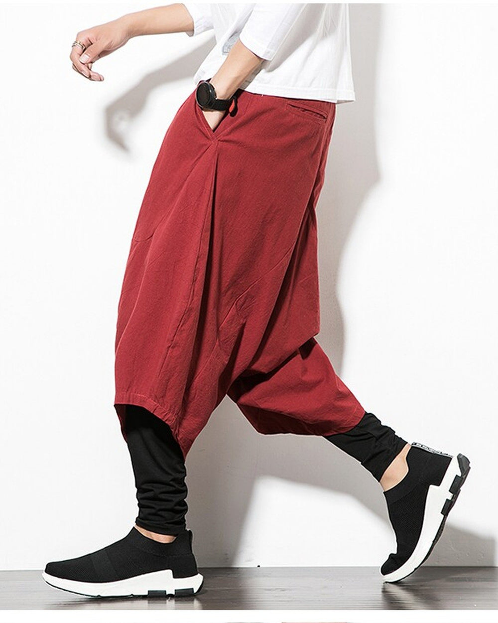 Wine red layered harem pants with a hand in the side pocket, showing the baggy outer layer
