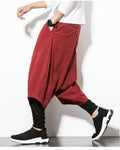 Wine red layered harem pants with a hand in the side pocket, showing the baggy outer layer