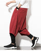 Wine red layered harem pants with a hand in the side pocket, showing the baggy outer layer