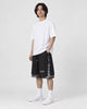 Model wearing the black layered paisley snap-side shorts with a white tee and white sneakers, three-quarter view