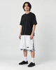 Model wearing the white layered paisley snap-side shorts with a black tee and black sneakers, three-quarter view