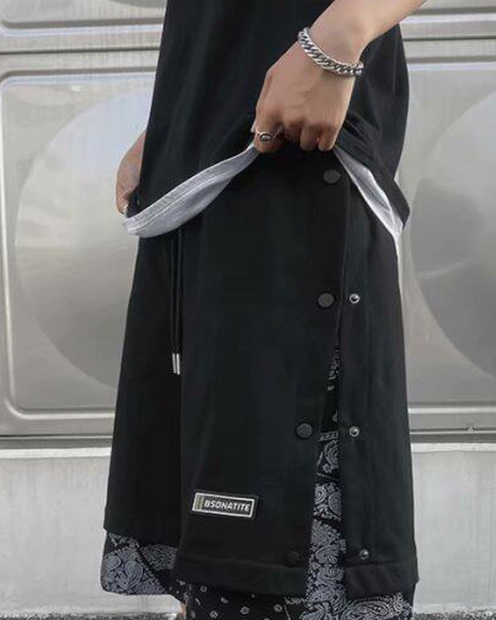 Front of the black snap-side shorts with a drawcord waist, woven label and paisley layer below the hem