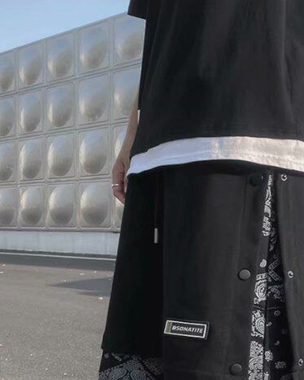 Side of the black snap-side shorts, with a row of metal snaps and the paisley layer showing at the hem