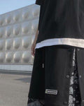 Side of the black snap-side shorts, with a row of metal snaps and the paisley layer showing at the hem