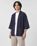 Model wearing the navy linen haori cardigan open over a white tee and stone trousers, three-quarter view