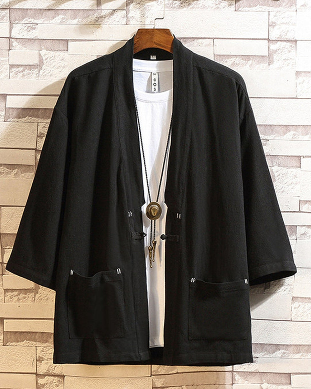 Black linen haori cardigan hanging open over a white tee, showing the patch pockets and the cloth toggle