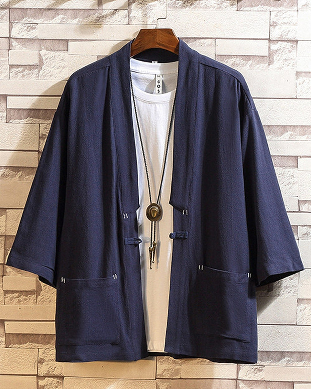 Navy linen haori cardigan hanging open over a white tee, showing the patch pockets and the cloth toggle