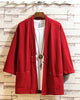 Red linen haori cardigan hanging open over a white tee, showing the patch pockets and the cloth toggle
