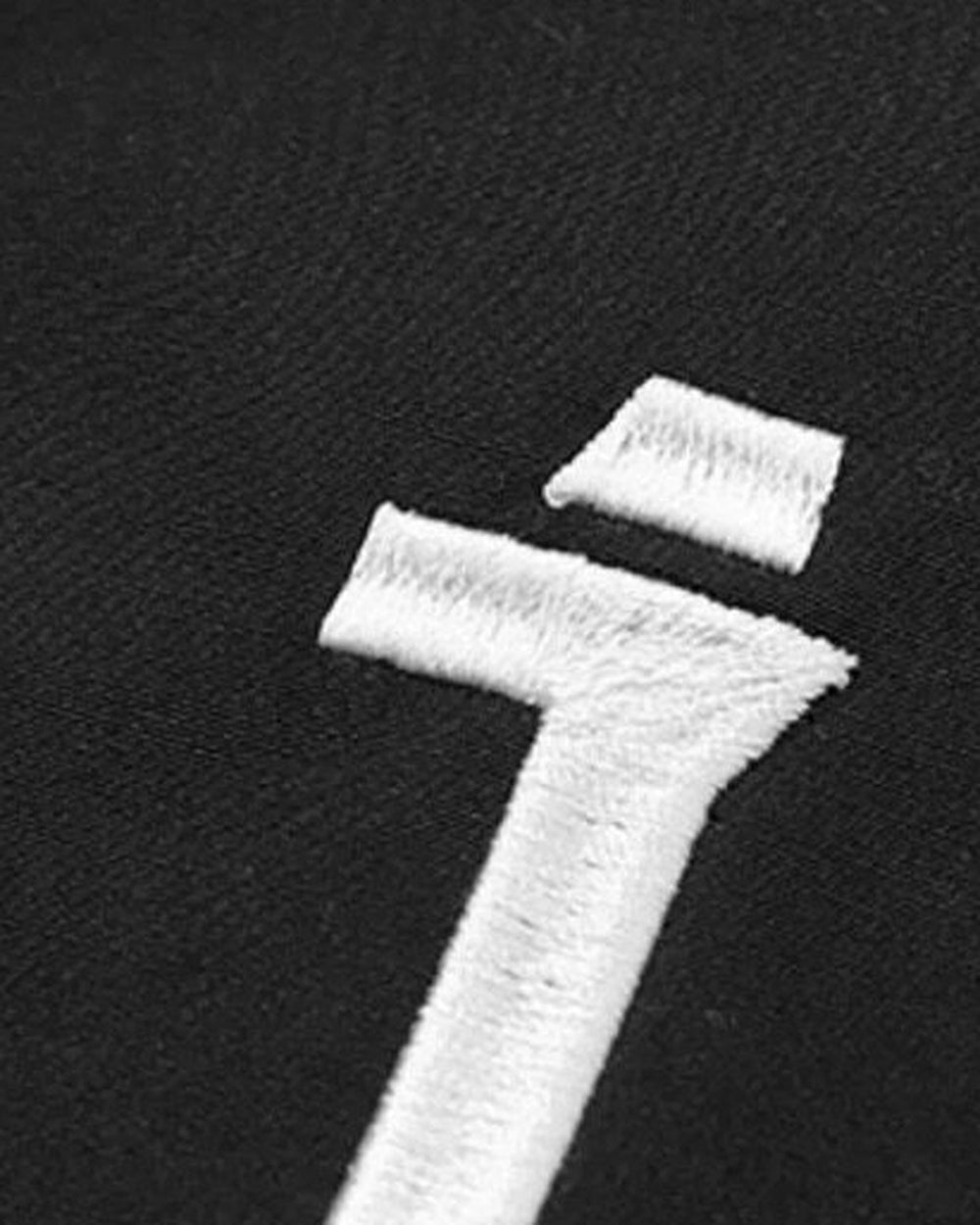 Close view of the white embroidered logo on the black jacket