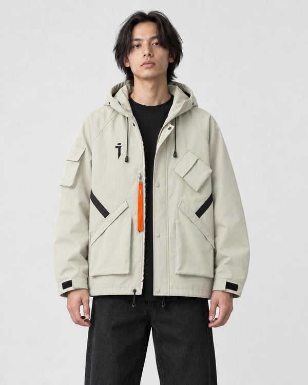Man in a beige hooded techwear jacket with an orange zip pull over a black tee, torso to mid-thigh