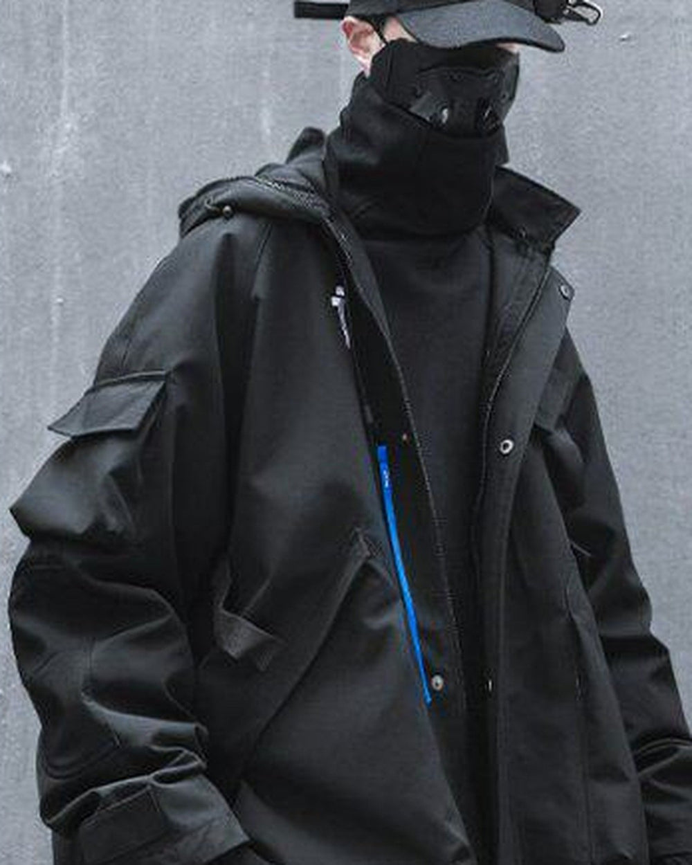 Man in the black hooded jacket with the hands in the pockets, three-quarter view of the front