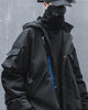 Man in the black hooded jacket with the hands in the pockets, three-quarter view of the front