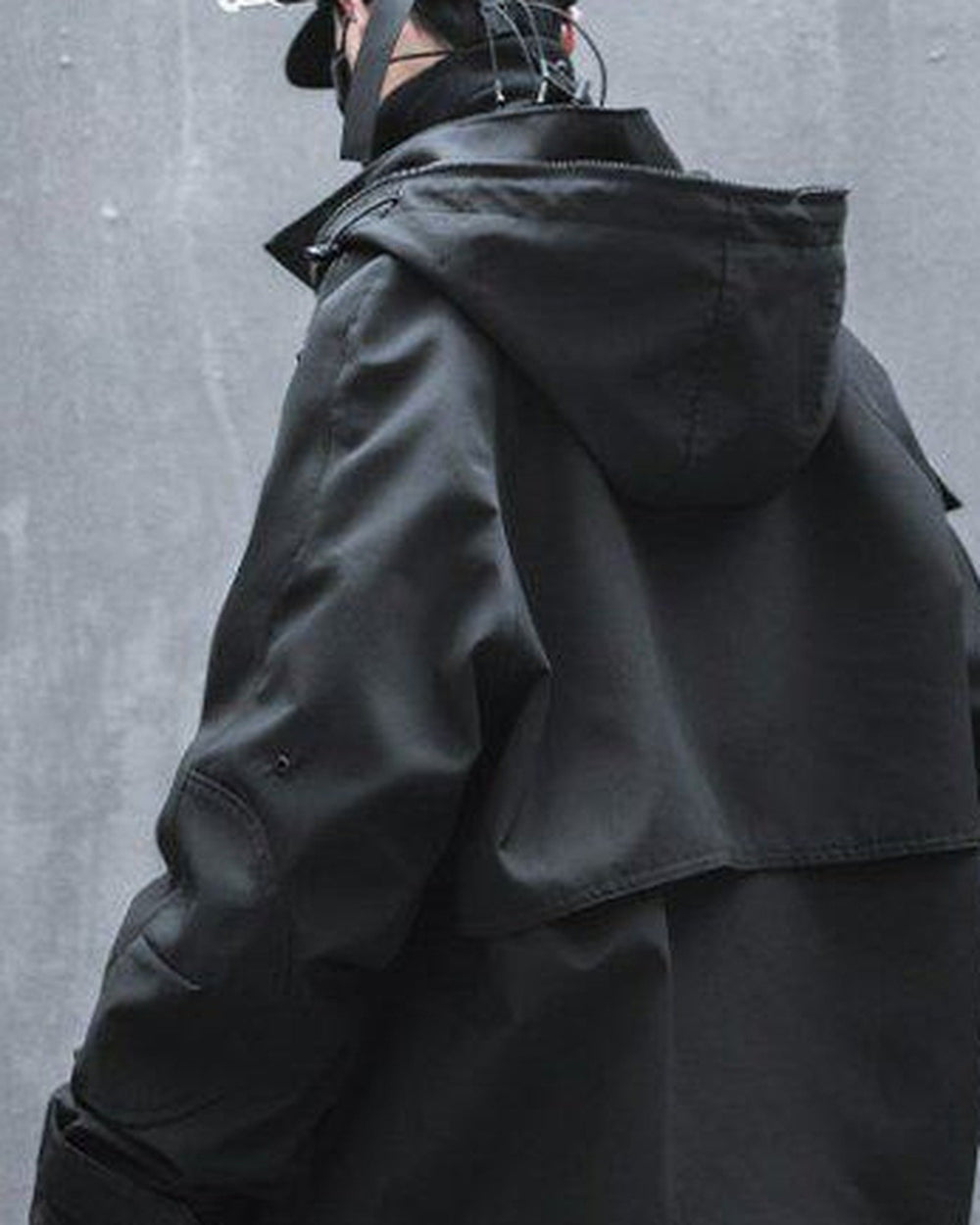 Back three-quarter view of the black hooded jacket showing the hood and the lower back panel