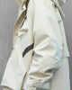 Side view of the beige hooded jacket showing the sleeve pocket and the hem
