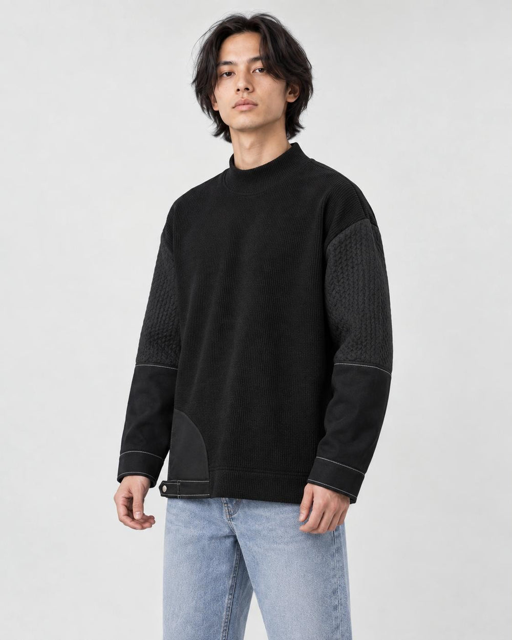 Man in the black mock-neck sweatshirt turned slightly, showing the sleeve panels and stitching