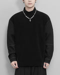 Man wearing the black mock-neck sweatshirt with a pearl chain necklace, front view