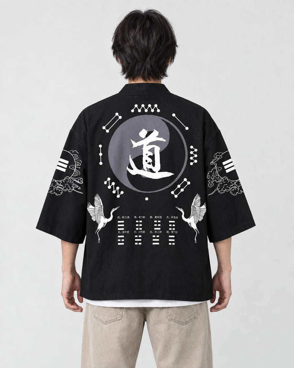 Man seen from behind in a black haori with a large gray 道 circle and two cranes on the back
