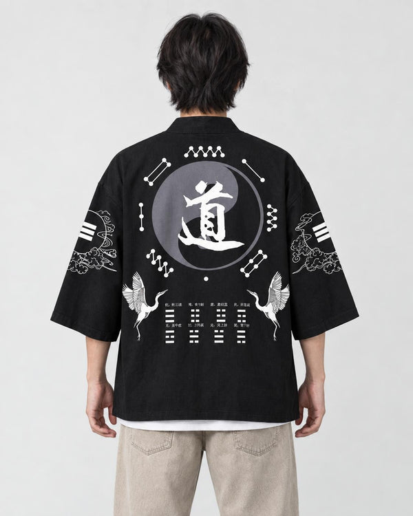 Man seen from behind in a black haori with a large gray 道 circle and two cranes on the back