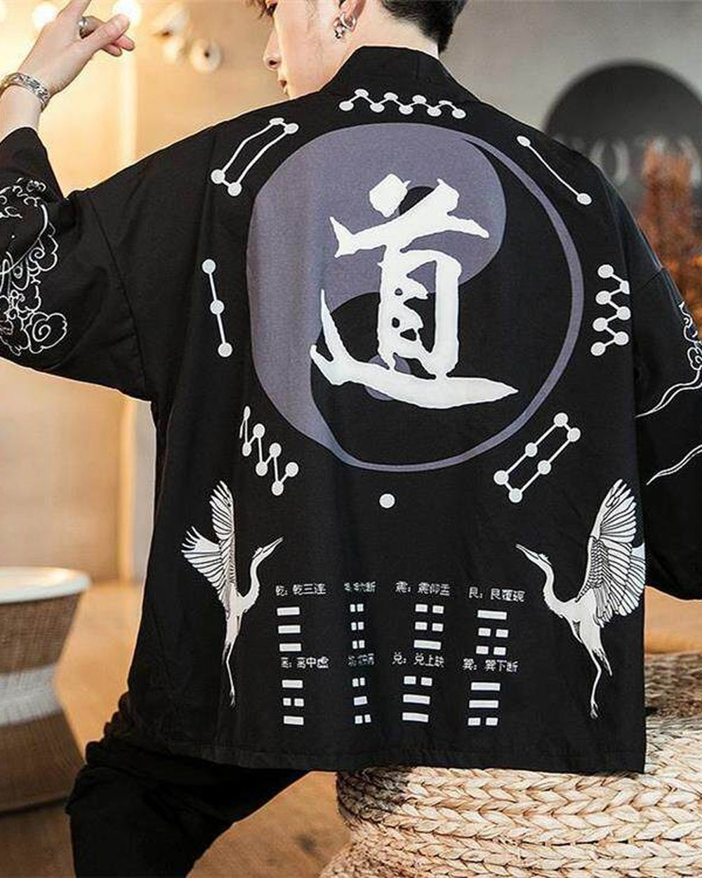 Man in the black 道 haori seen from behind with his arms raised