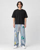 Model wearing the light blue paint-splatter wide-leg jeans with a black tee and white sneakers, front view